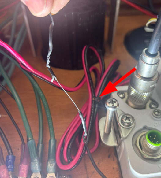 Factory wire tie on VHF radio power cable with steel core contacting exposed positive terminal — resistive heating damage found during marine electrical safety inspection San Francisco Bay Area